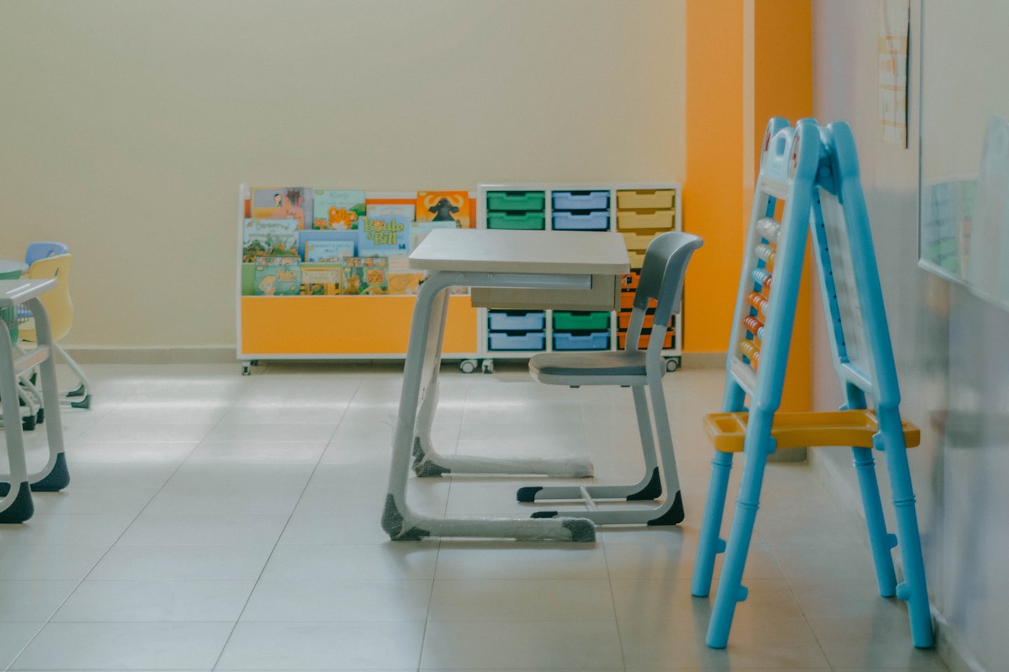 Modern desk and chair in a bright classroom with colorful books.